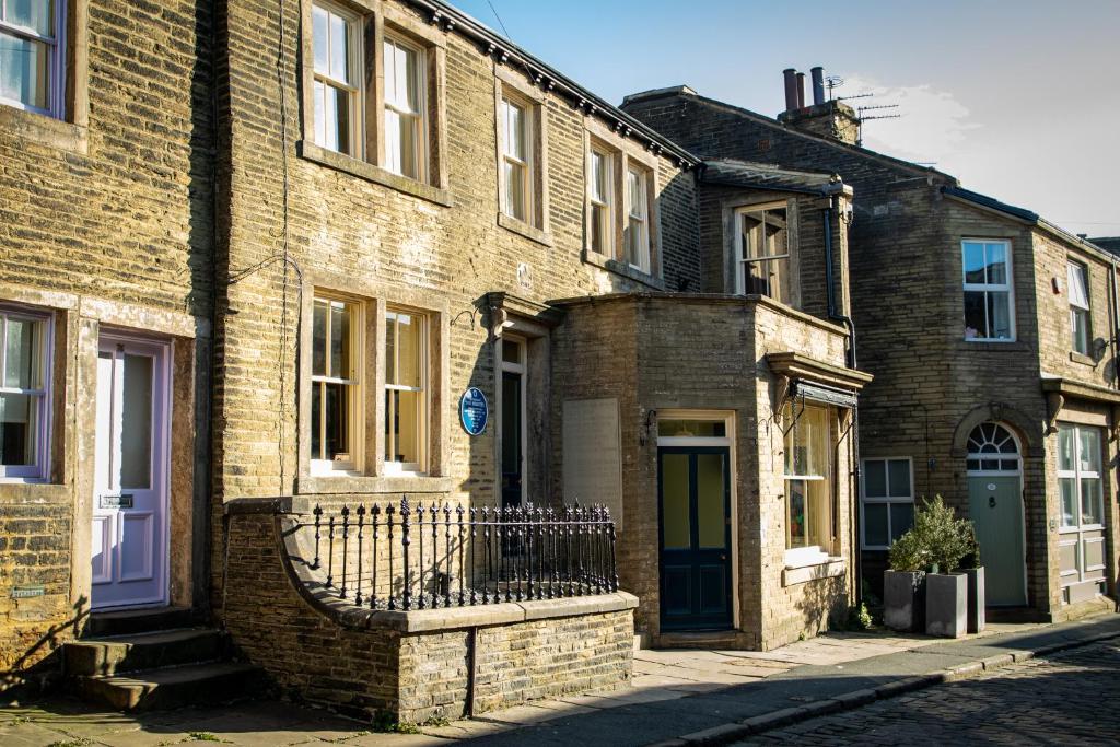 a brick building with a gate on a street at The Brontë Birthplace in Thornton