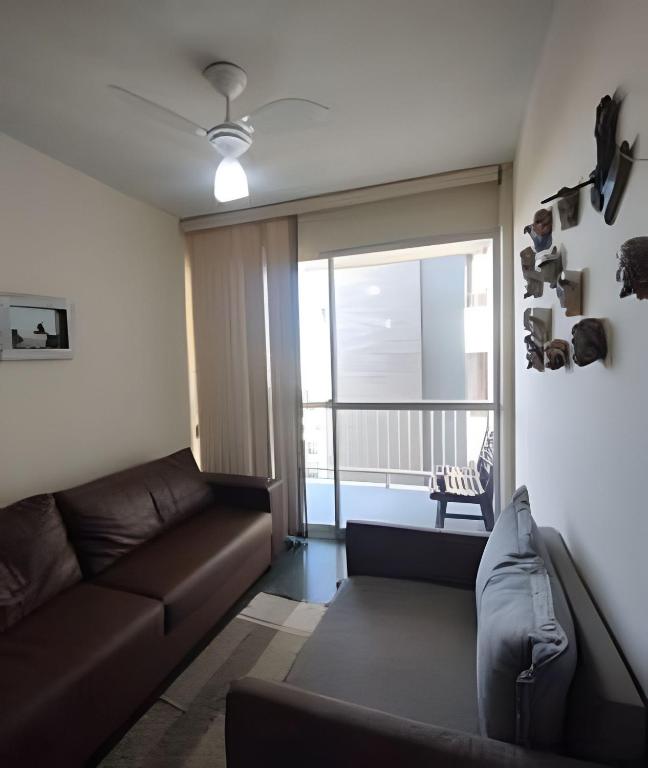 a living room with a couch and a large window at Cobertura com 4 quartos e ar condicionado in Cabo Frio