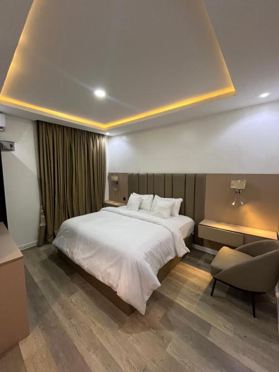una camera da letto con un grande letto bianco e una sedia di Sweet Home hotel a Lekki