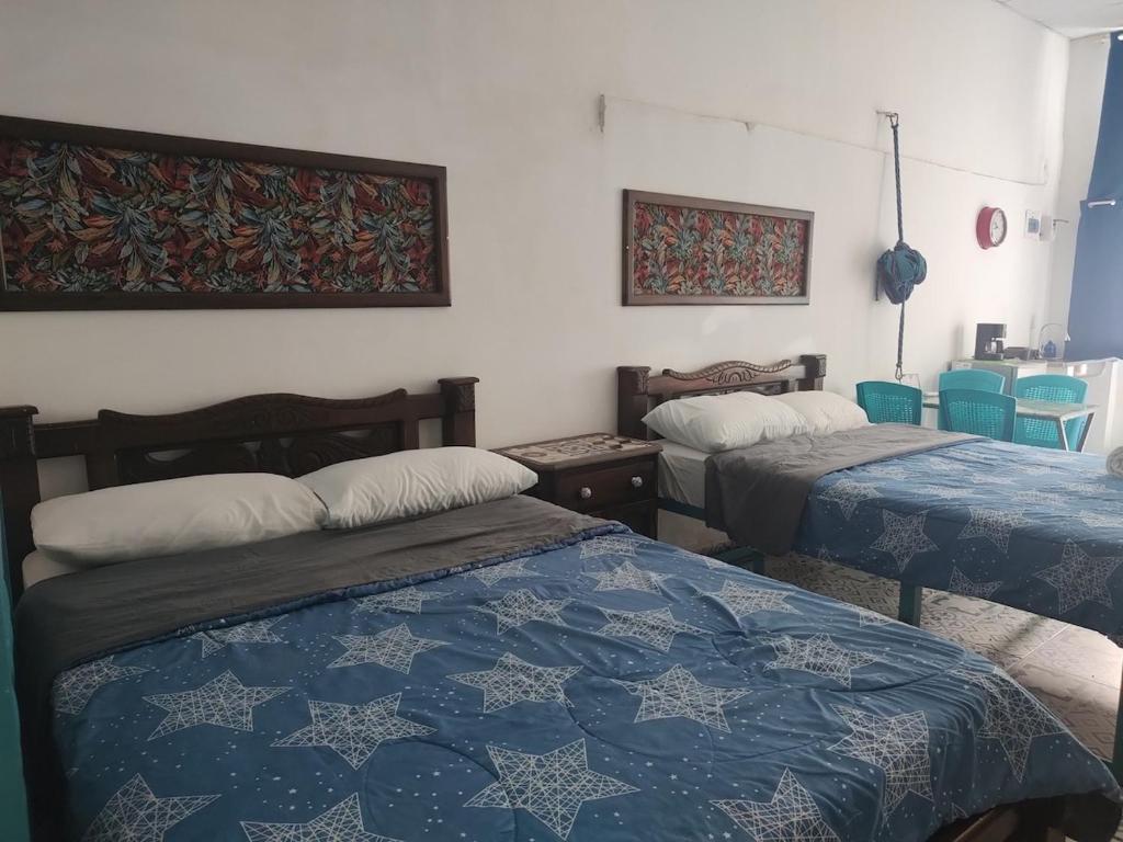two beds in a room with blue and white sheets at BALLESTRINQUE - GETSEMANI- CARTAGENA DIVINa in Cartagena de Indias