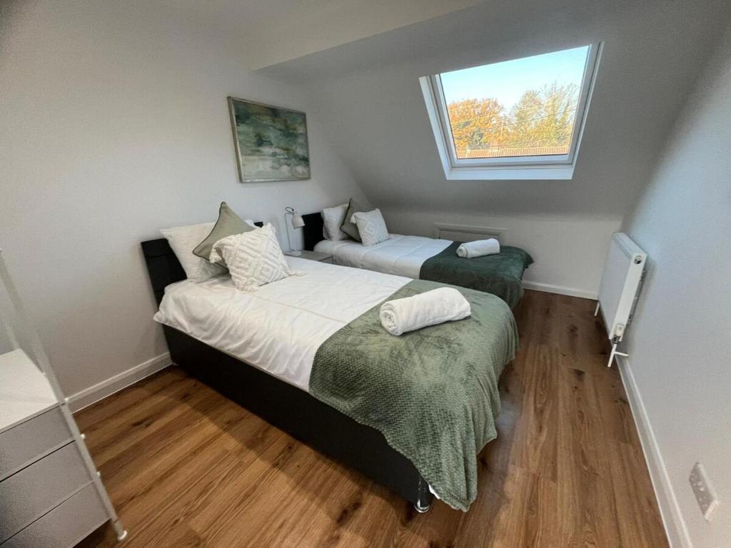 Woodfield Cottage Crawley 3 BR,Parking,Wifi,Garden, nearby Gatwick Airport, Contractor friendly, temporary relocations, business travellers, families في كراولي: سريرين في غرفة صغيرة بها نافذة