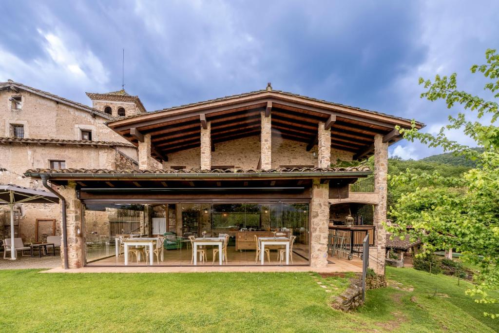 an external view of a villa with a patio with tables at Hotel Mas la Ferreria in La Vall de Bianya