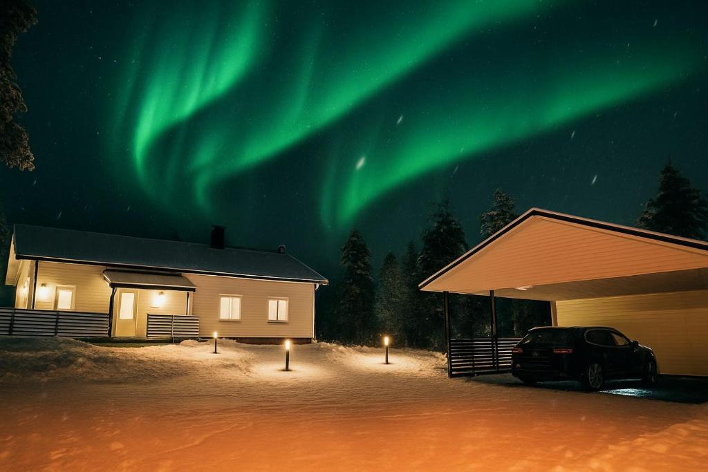 a car parked in front of a house under the aurora at Villa Arctic star in Rovaniemi