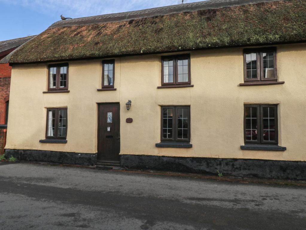 a yellow house with a grass roof at Bridge Cottage in Budleigh Salterton