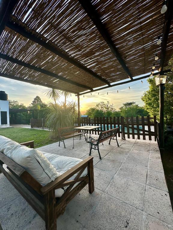 a patio with two benches and a wooden pergola at Casa Familiar Villa Carlos Paz in Villa Carlos Paz