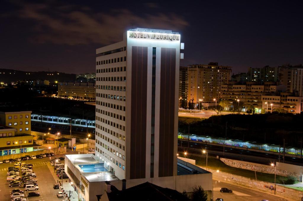 un edificio con un cartel encima por la noche en VIP Executive Zurique Hotel en Lisboa