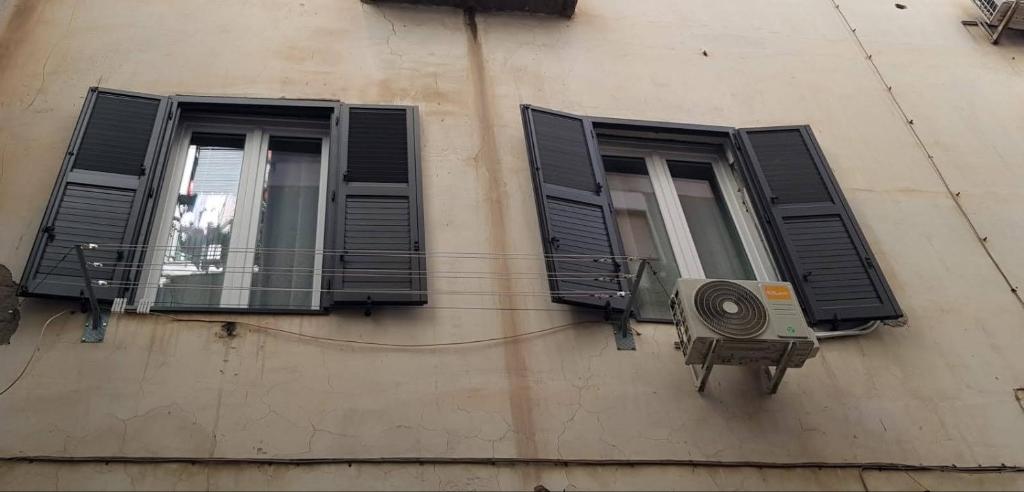 two windows with black shutters on a building at casa di Francesco e Azzurra in Torre del Greco