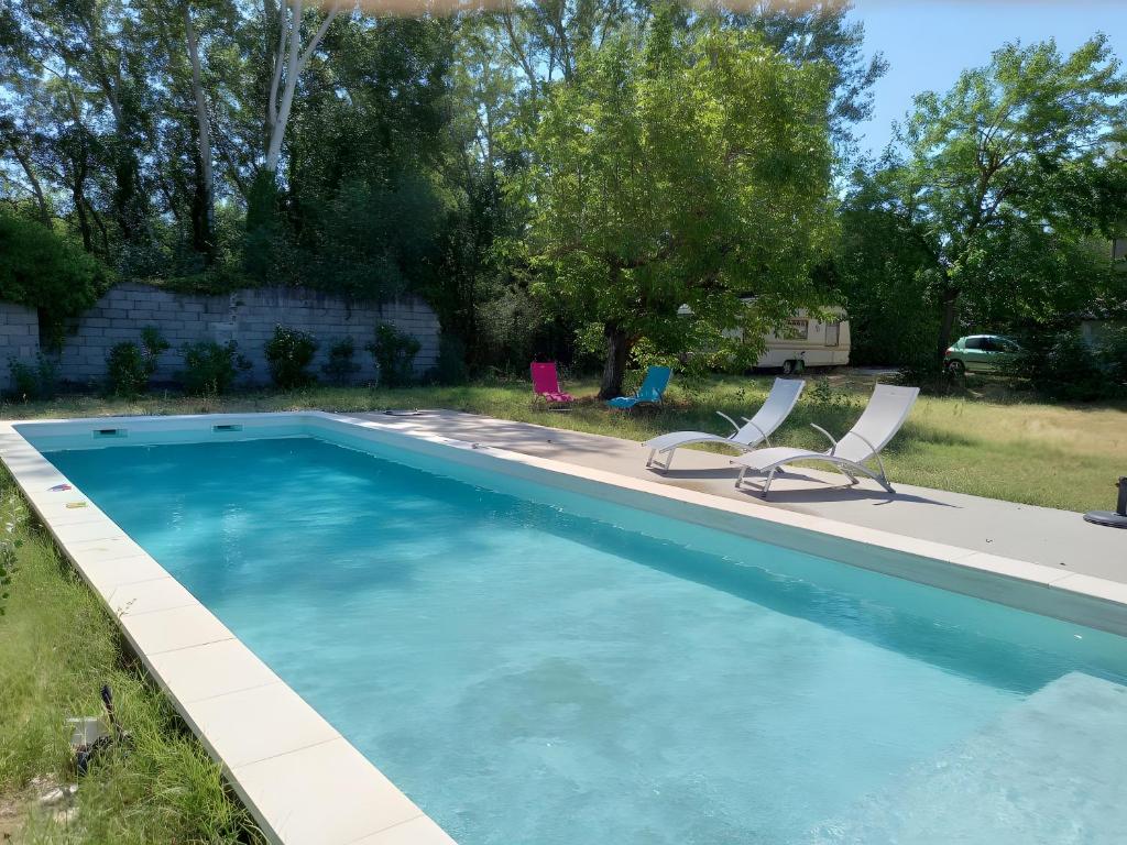 une piscine avec deux chaises longues et une piscine dans l'établissement Gîte Harmony, à Châteauneuf-du-Rhône