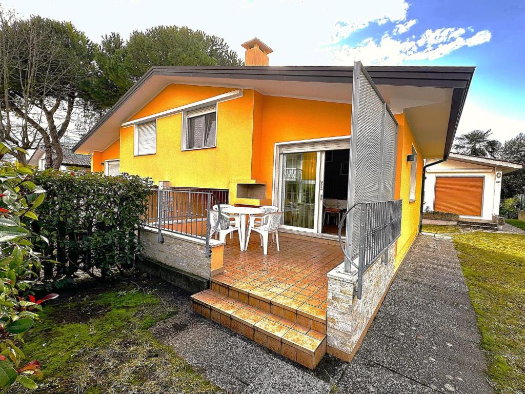 una casa gialla con terrazza e tavolo di Comfy villa in central location a Bibione