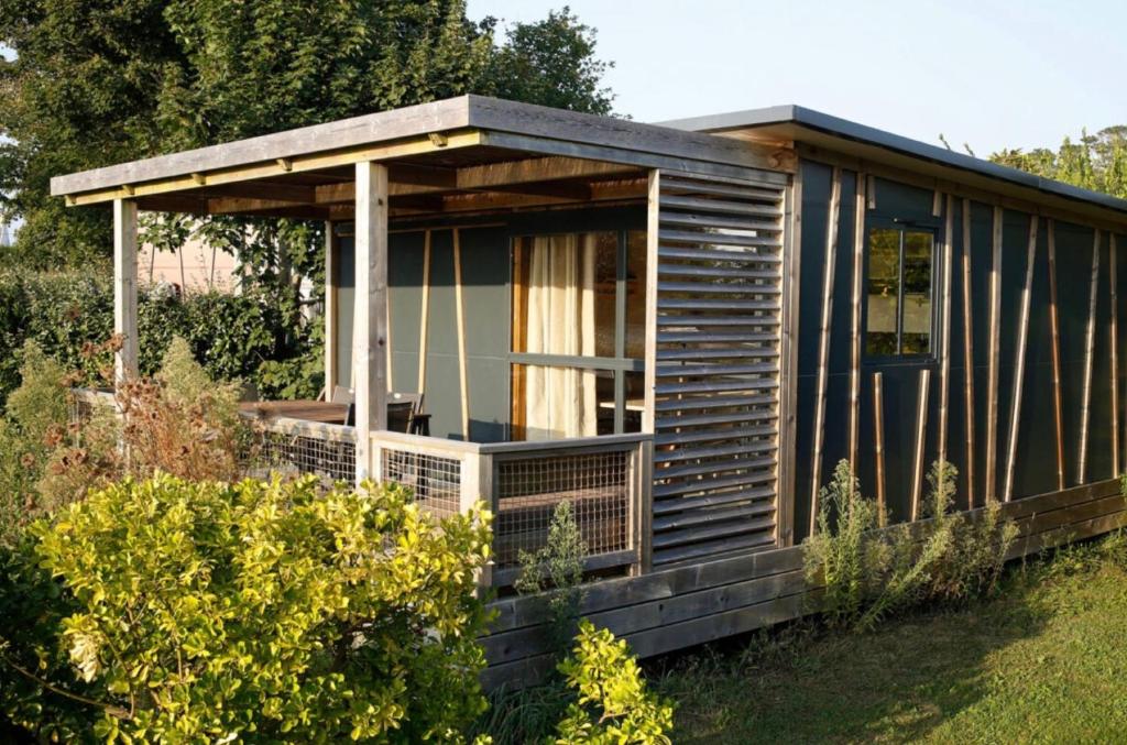 a wooden cabin with a porch in a garden at Chalet 25m2 - Pierres Noires in Plouhinec