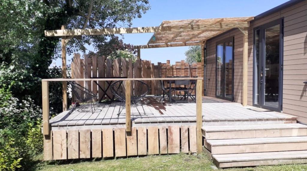 a wooden deck with a table and a fence at Mobil-home neuf - Au bleu du ciel in Plouhinec