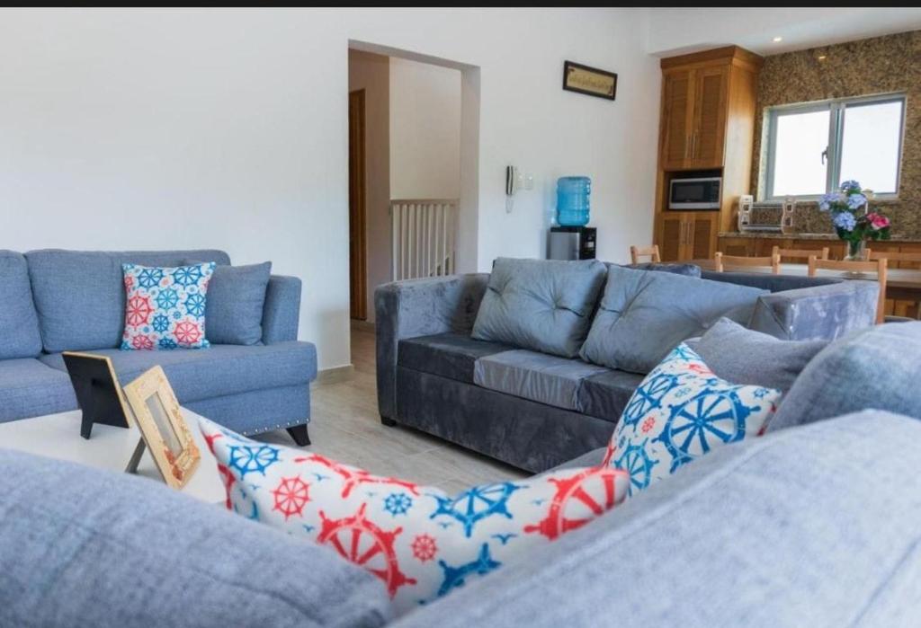 ein Wohnzimmer mit 2 blauen Sofas und einer Küche in der Unterkunft Paradise Found 3Bedroom Apartment with Pool in Las Terrenas