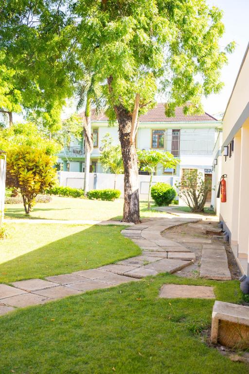 a tree in front of a house with a sidewalk at Salt Garden Inn in Dar es Salaam