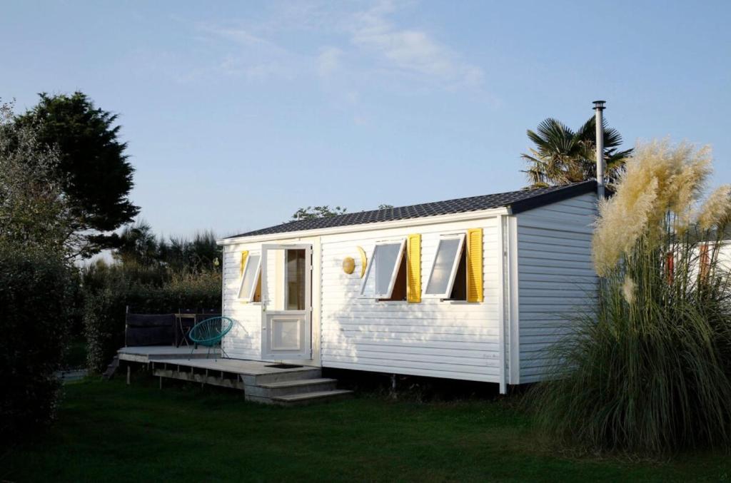 a small white tiny house in a yard at Mobil-home Les volets jaunes in Plouhinec