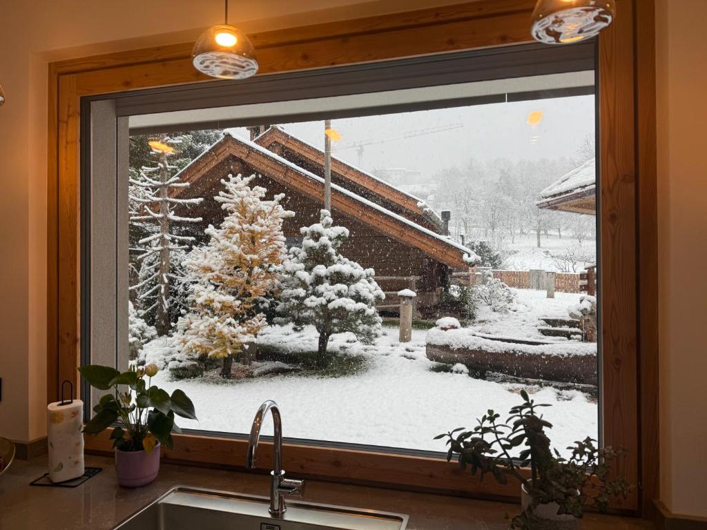 ventana de cocina con vistas a un patio cubierto de nieve en Alaska House Suite Bering - sauna and relax, en Trento