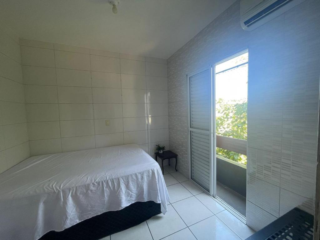 a bedroom with a bed and a large window at Casa de Praia- Suíte São Lourenço in Bertioga