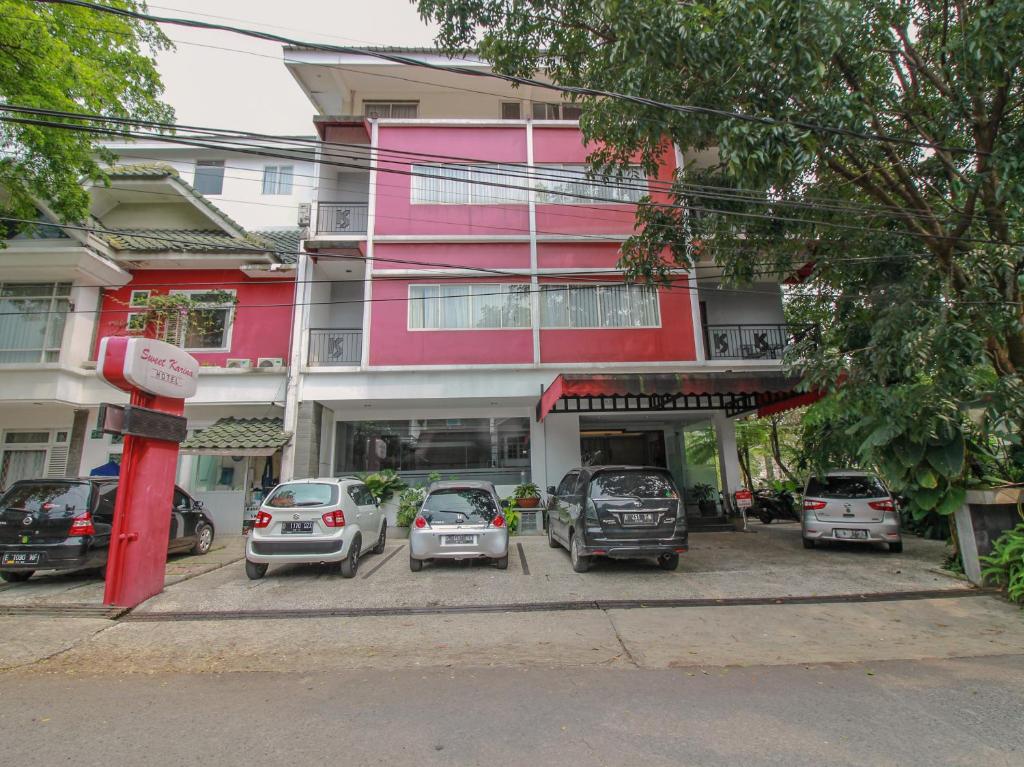 a group of cars parked in front of a pink building at Sweet Karina Hotel Pasteur in Bandung