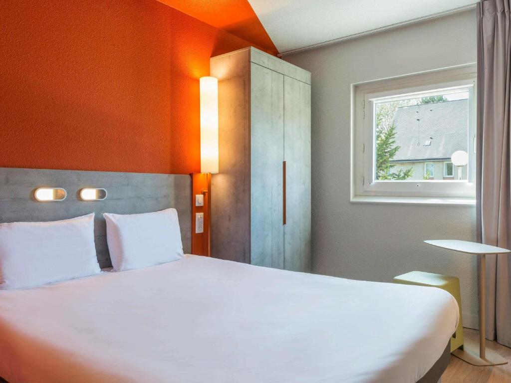 une chambre avec un grand lit blanc et une fenêtre dans l'établissement ibis budget Senlis, à Senlis