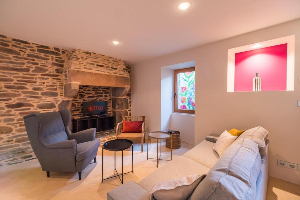 ein Wohnzimmer mit einer Couch und einer Steinwand in der Unterkunft Sejour prestige a Lannion entre ville et plages in Lannion