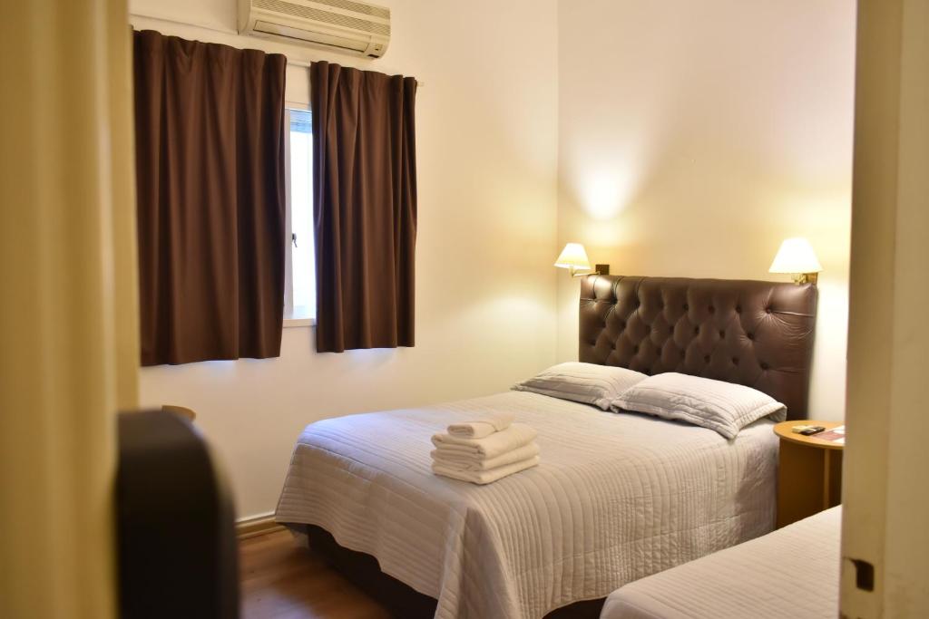 a hotel room with two beds and two windows at Hotel Frossard in Buenos Aires