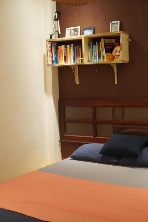 a bedroom with a bed and a shelf with books at Hostel-John Cafe and Beer in Da Lat