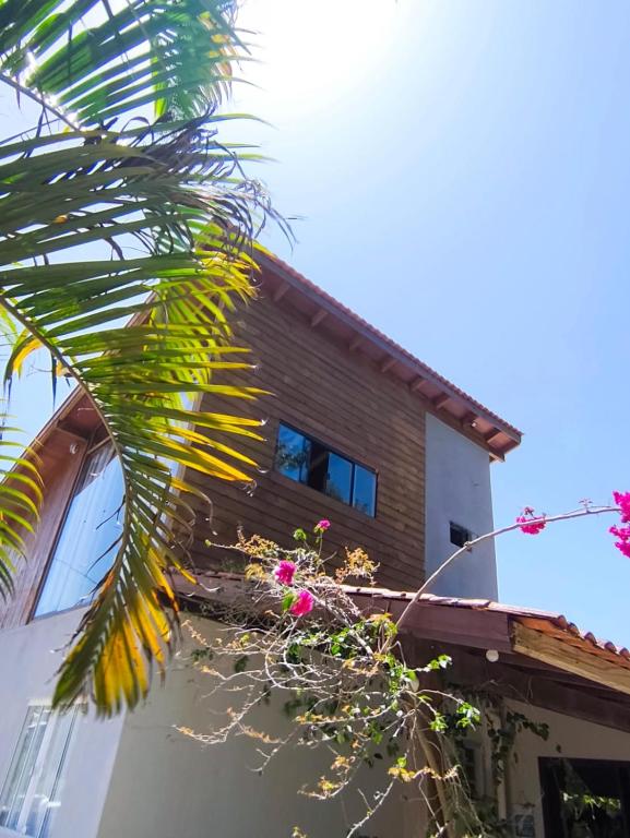 a house with a palm tree in front of it at Apartamento de 2 Quartos para 4 Pessoas - 5 min da Praia in Garopaba