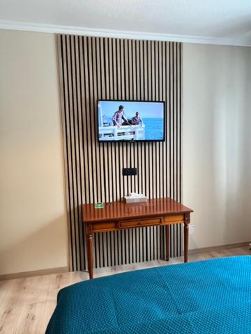 Zimmer mit einem TV an der Wand und einem Tisch in der Unterkunft Hôtel l'Orée des Roches in Saales