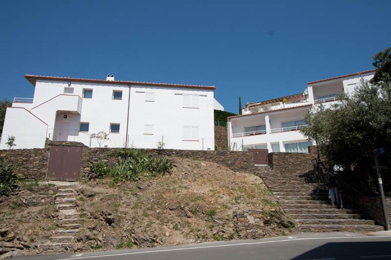 a white building on top of a hill with stairs at Aparthotel l'Heretat in Cadaqués