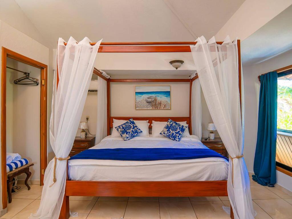 ウェスト・ベイにあるBonsai rentals - West Bay Private Roomsのベッドルーム(青い枕と天蓋付きベッド付)