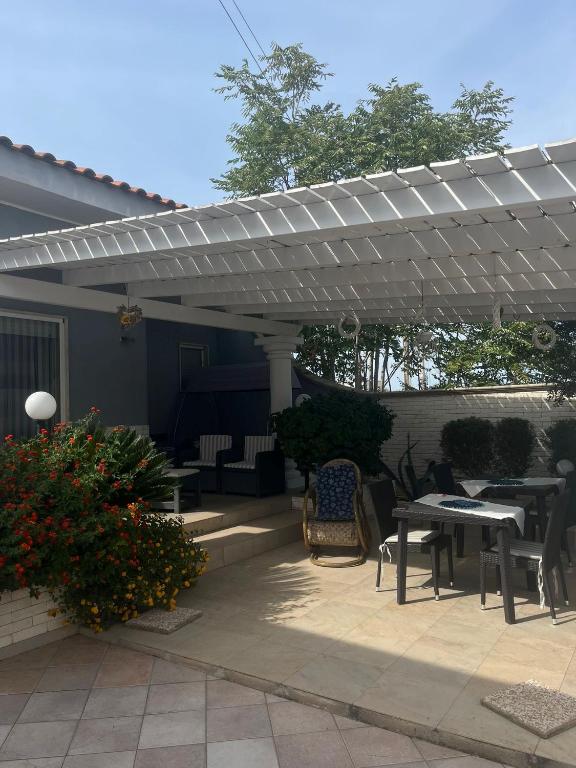 patio con tavoli e sedie sotto un pergolato di Villa Miglietta a Torre Lapillo