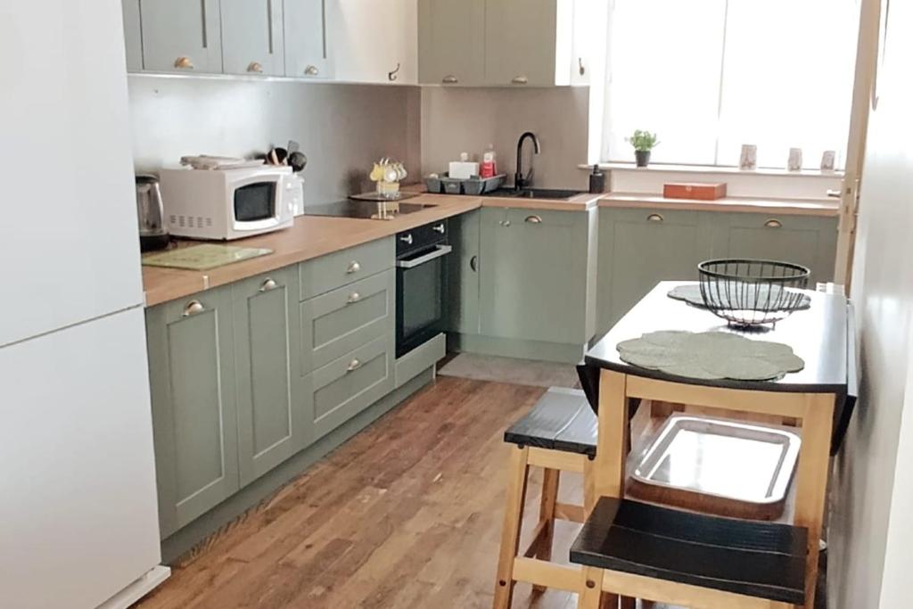 ImphyLe Havre de Sauge的厨房配有绿色橱柜、桌子和微波炉