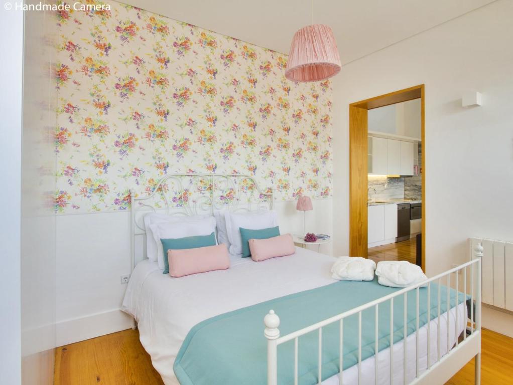 a bedroom with a white bed with pink and blue pillows at Charming Apartments in Historic Centre - Inside Porto Apartments "Flores" in Porto