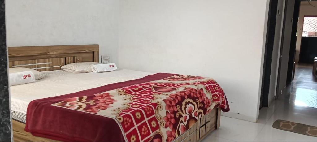 um quarto com uma cama com um cobertor vermelho em Junglee Valley Holiday Home em Mahabaleshwar