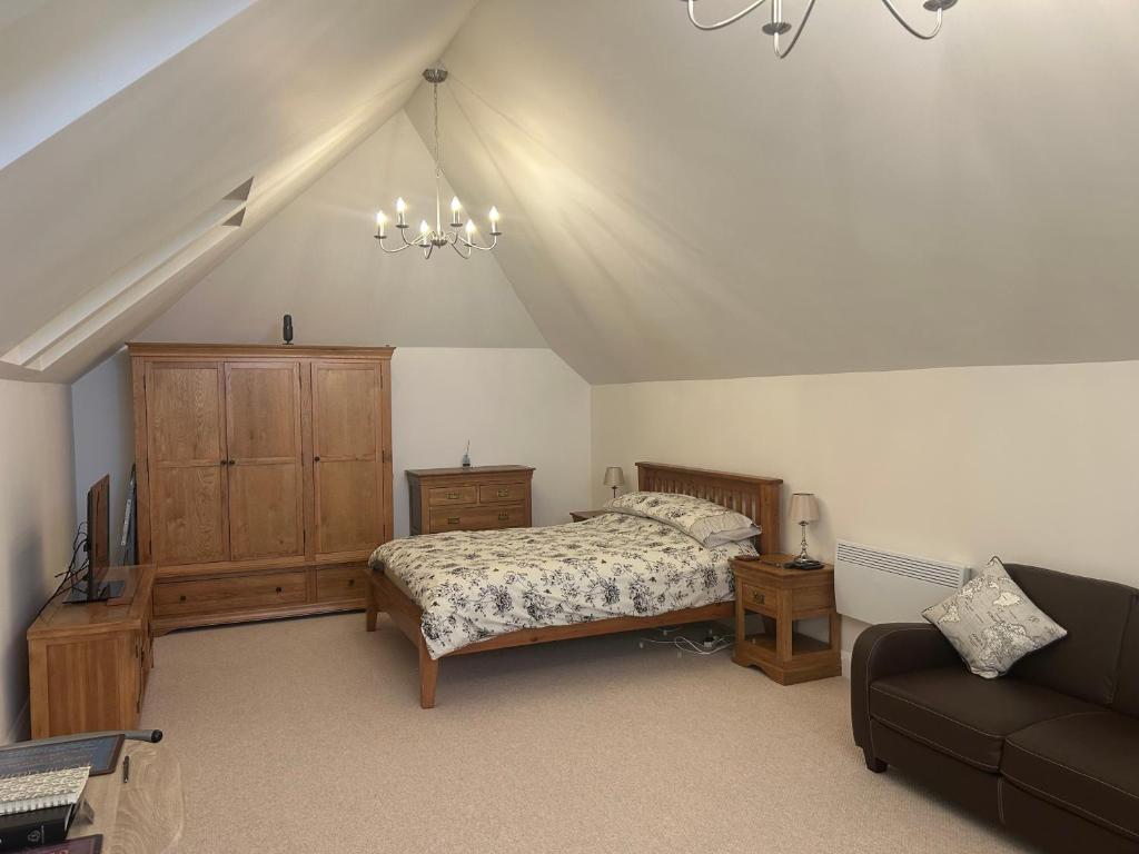 a bedroom with a bed and a couch at Charming King Bed Ensuite Studio in Peaceful West Challow in Wantage