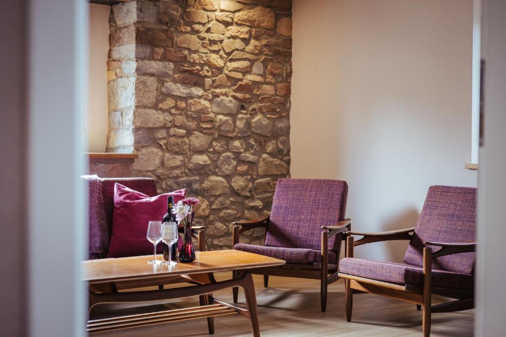 a room with two chairs and a table with wine glasses at Im Prummehuck in Raeren