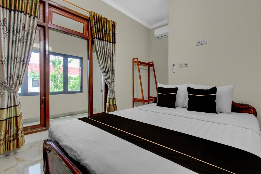 um quarto com uma cama grande e almofadas pretas e brancas em OYO 94920 House Of Elea Minggiran em Timuran