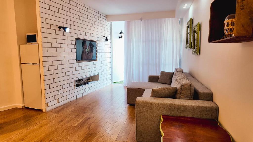 Una sala de estar con un sofá y una pared de ladrillos. en Leo Apartment by the sea Eilat, en Eilat