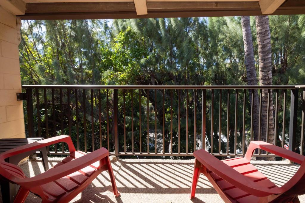 twee rode stoelen op een veranda met een leuning bij Hono Kai Resort C9 in Wailuku