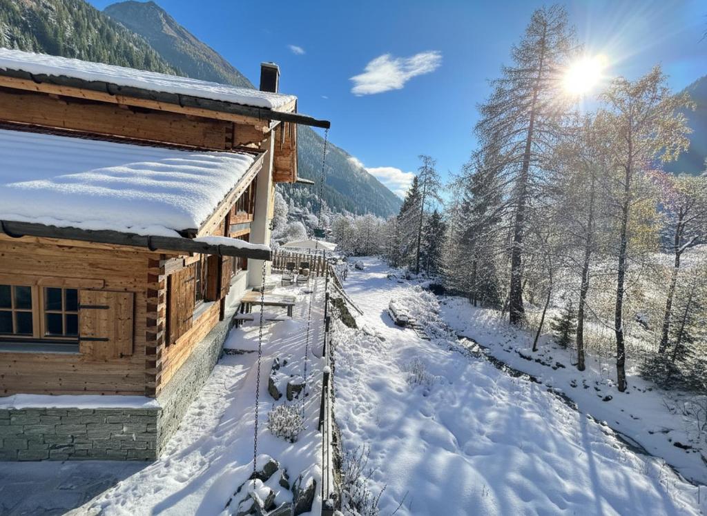 una cabaña de madera en la nieve junto a un río en Chalet am Bachl 2, en Flattach