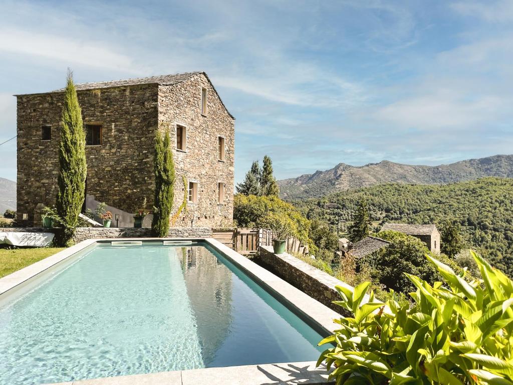 a pool in front of a building with mountains in the background at Casa Surgente in Carcheto