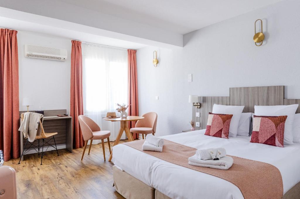 um quarto de hotel com uma cama grande e uma mesa em Maison des Croisades em Aigues-Mortes
