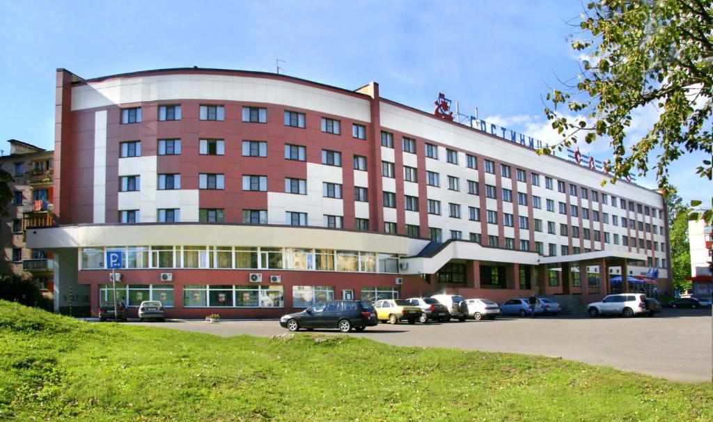 duży budynek z samochodami zaparkowanymi na parkingu w obiekcie Sadko Hotel w mieście Nowogród Wielki