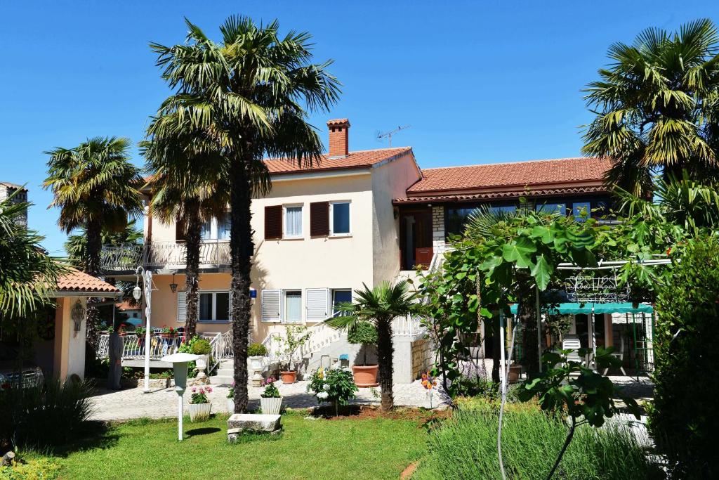a house with palm trees in front of it at Apartments Nela in Poreč