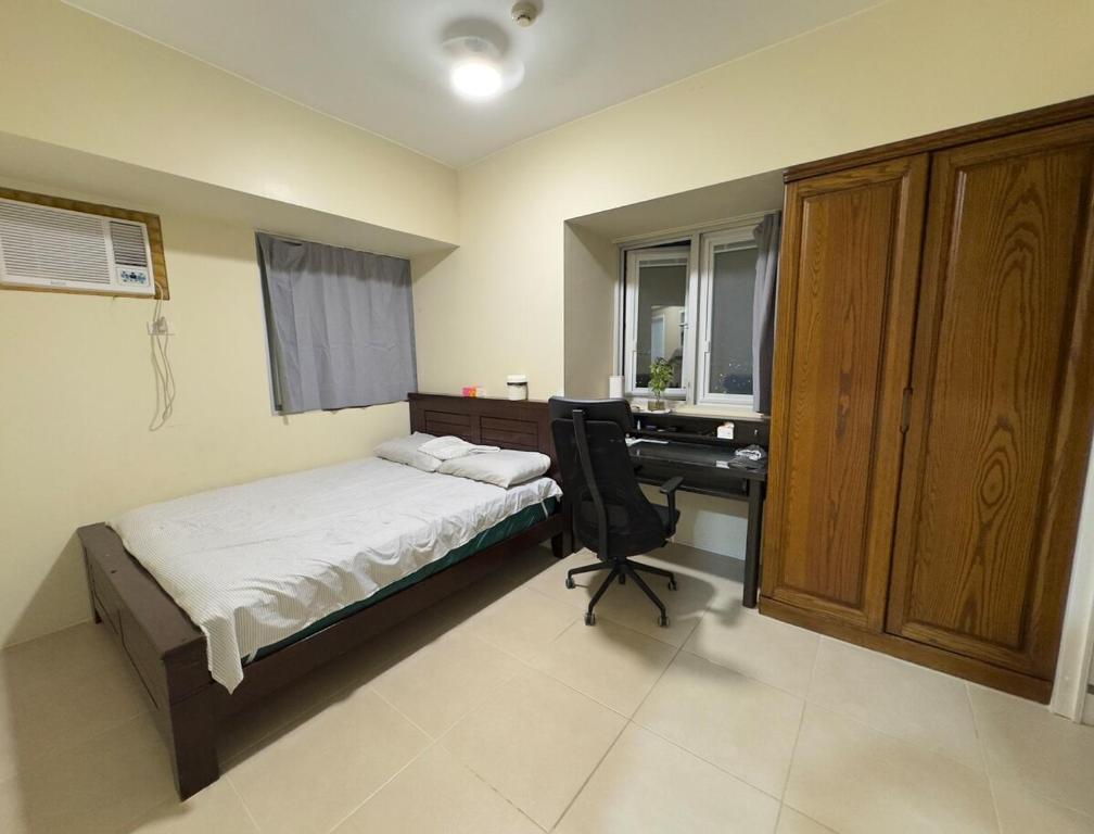 ein Schlafzimmer mit einem Bett und einem Schreibtisch mit einem Computer in der Unterkunft Leo's Master bedroom in Manila