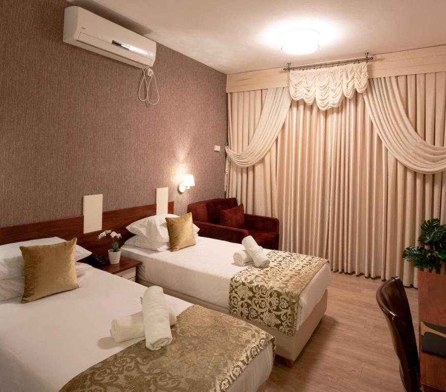 a hotel room with two beds and a couch at Aristocrat Hotel Haredi in Bnei Brak