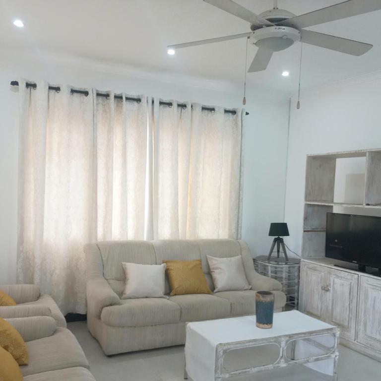 a living room with a couch and a ceiling fan at 200 on Genazzano in Densainagar