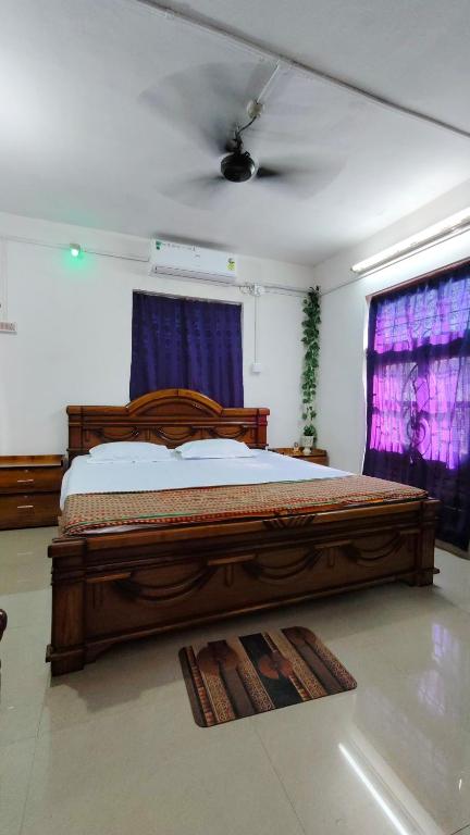 a bedroom with a large wooden bed with purple curtains at Amaravati homestay in Guwahati