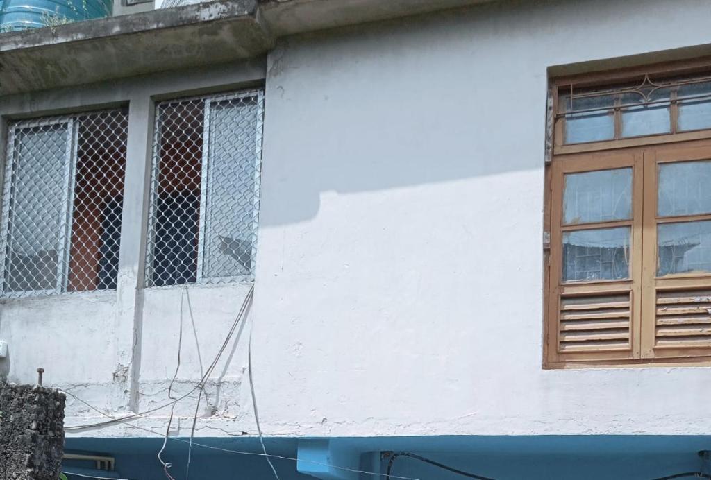 古瓦哈提Amaravati homestay的一栋带有木窗的白色建筑