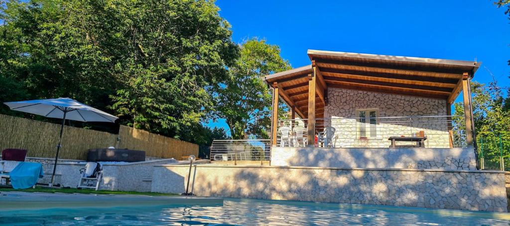 a house next to a swimming pool with an umbrella at Secret Garden in Grottolella