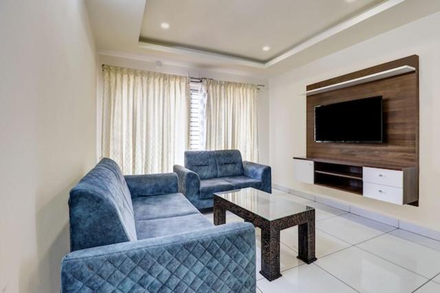 a living room with two blue chairs and a television at 5BHK AC Villa call 8O882 - 37972 in Mysore